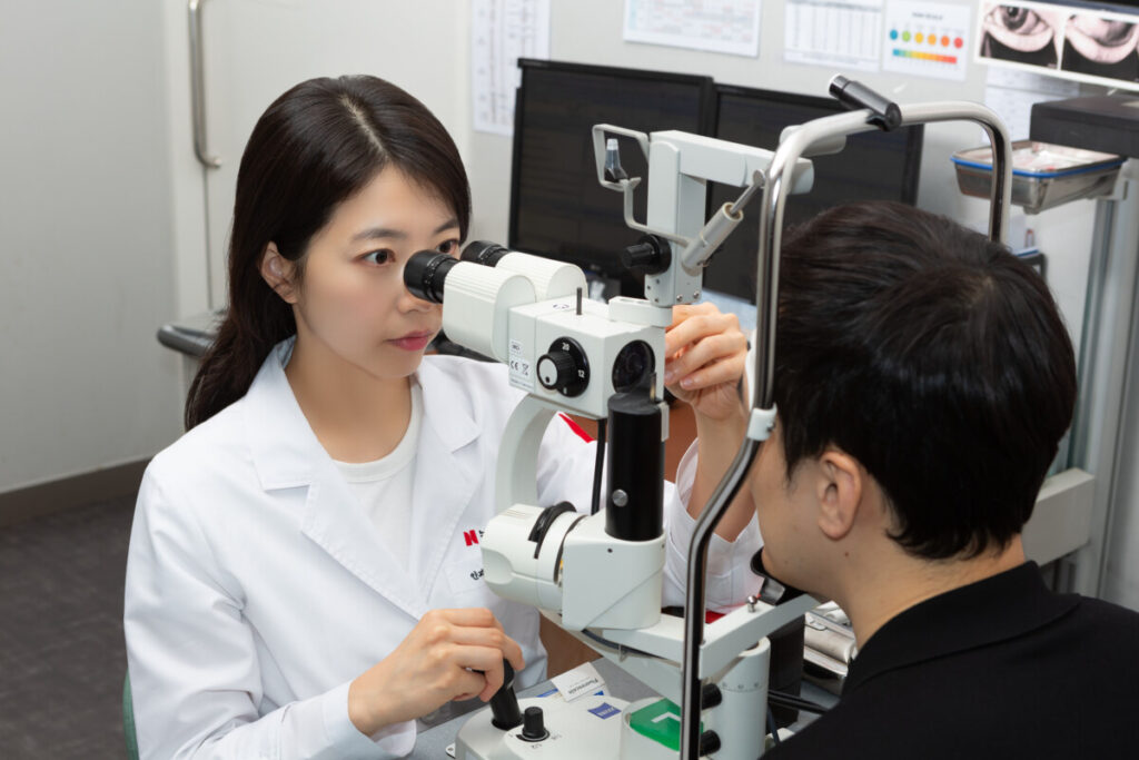 라식수술 전 정확한 검사를 위해 기계로 시력측정을 하고 있는 의료진과 진료받고 있는 환자